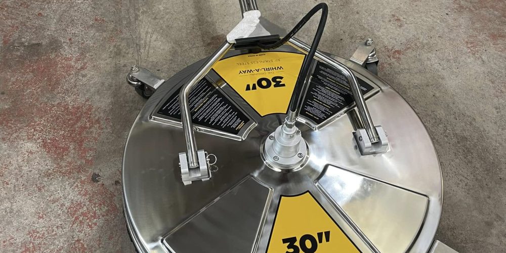 Close-up view of a mobile heavy-duty pressure washer pump manifold and internal heater coils being inspected and drained for winterization protection.
