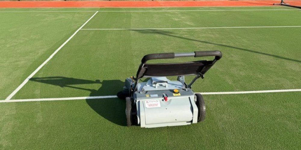Columbus SWL 700 ET Deluxe walk-behind electric sports sweeper groomer on a green synthetic grass tennis court.